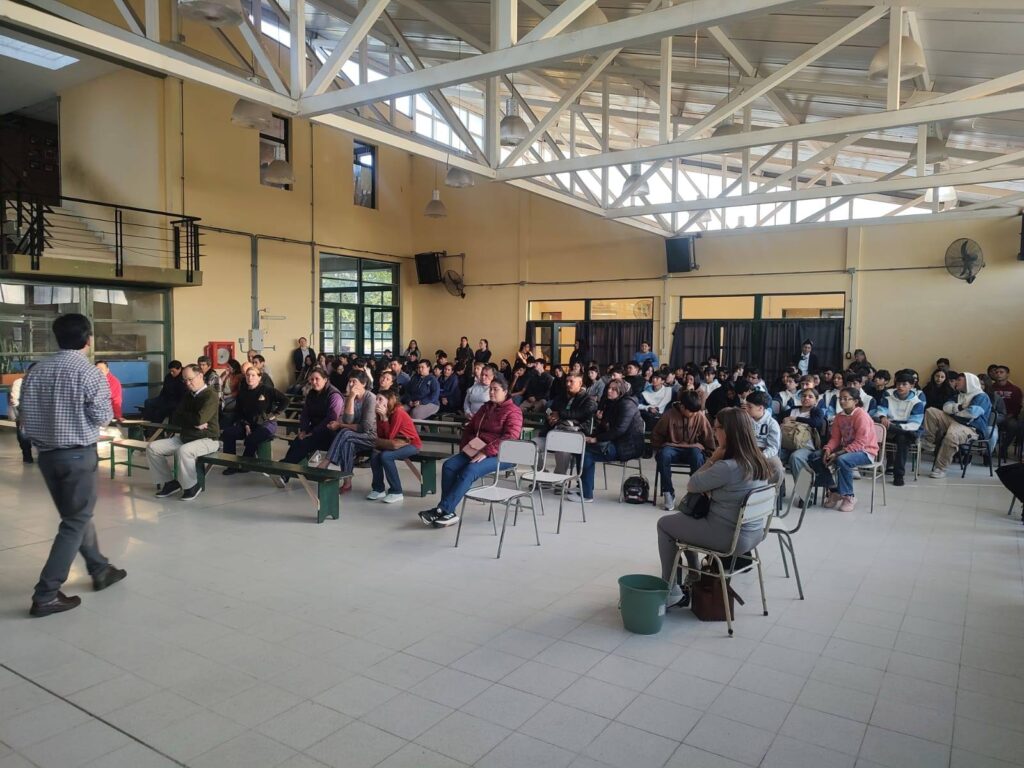 alt="Directivos y padres sentados en bancos de escuela durante una asamblea sobre infraestructura escolar en Concordia"
