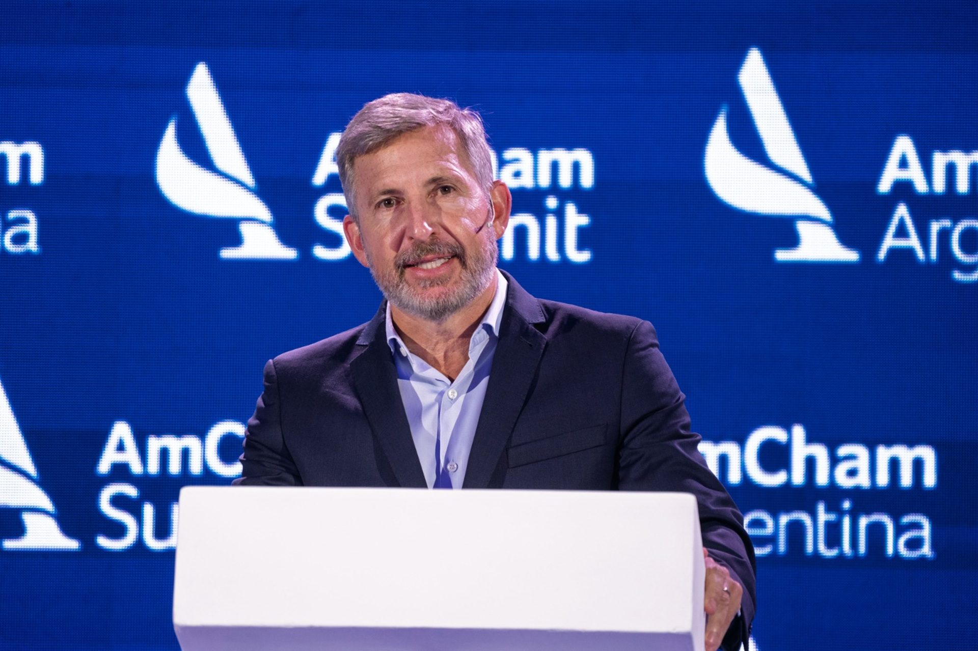 alt="Gobernador Frigerio habla en el podio del AmCham Summit 2026 proponiendo un nuevo acuerdo fiscal federal"
