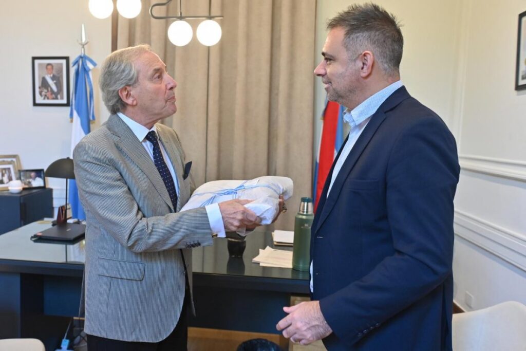 alt="Mauricio Davico entrega un regalo artesanal al artista Pipo Pescador en Gualeguaychú en una oficina municipal"