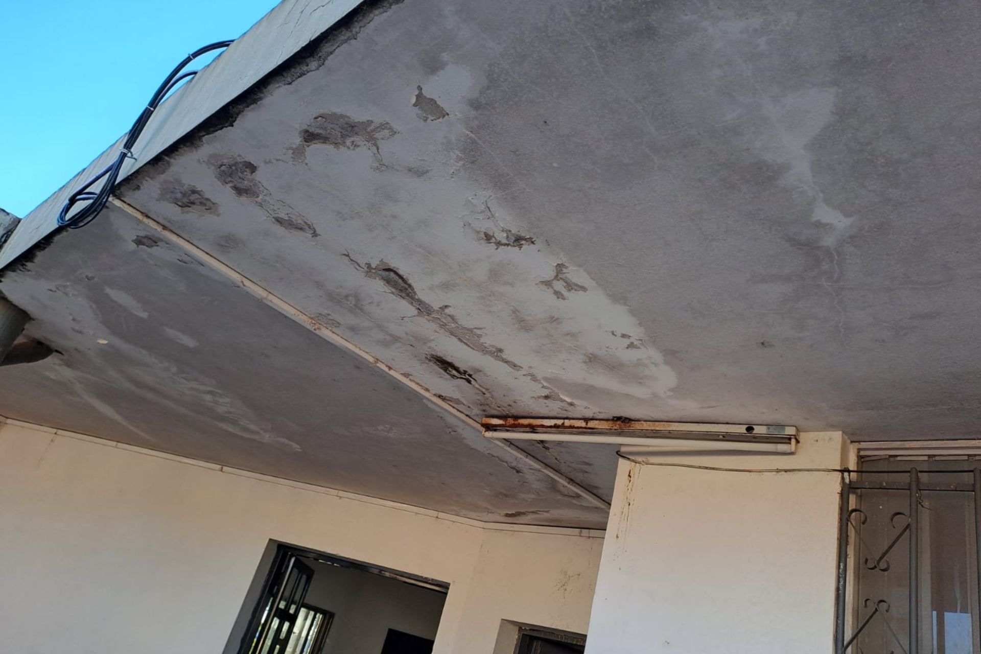 alt="Primer plano de cielorraso descascarado y con humedad previo a la reparación de la Escuela Artigas de Concordia"