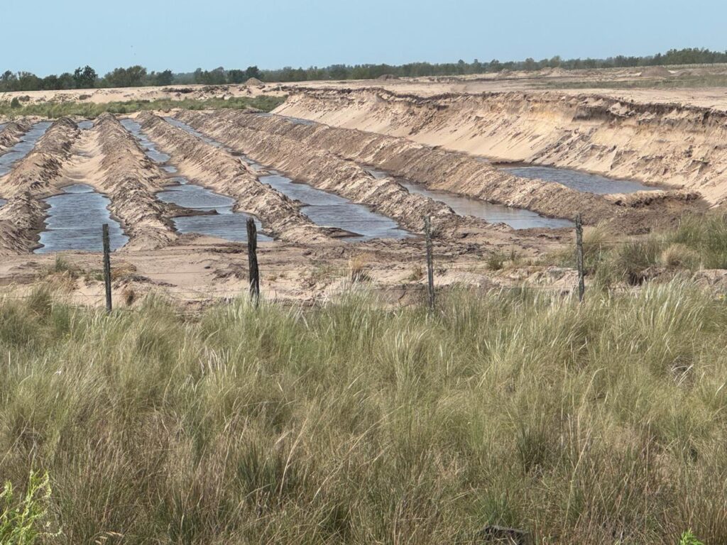 alt:="Zona de extracción de arena silícea en Ibicuy, Entre Ríos, para Vaca Muerta, con depresiones y agua aflorante en el paisaje de dunas (foto: Rubén Quintana)"