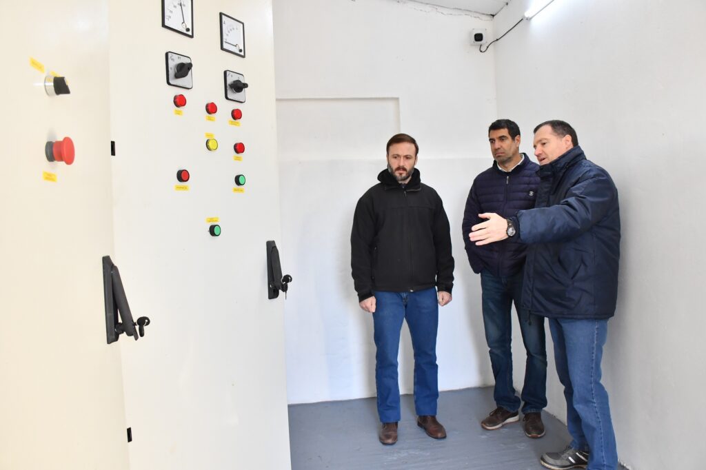 alt="Plano medio de tres personas conversando frente a los selectores de los tableros de comando manual/automático"