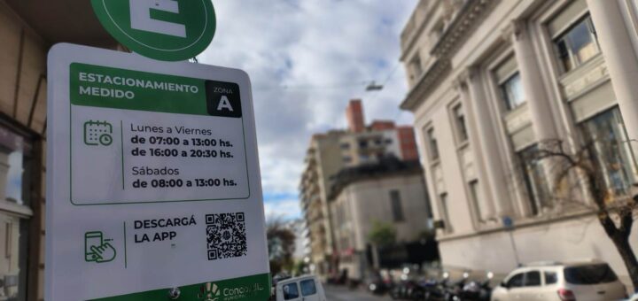 aqlt="Cartel verde del nuevo sistema de estacionamiento medido en Concordia indicando horarios y descarga de app"