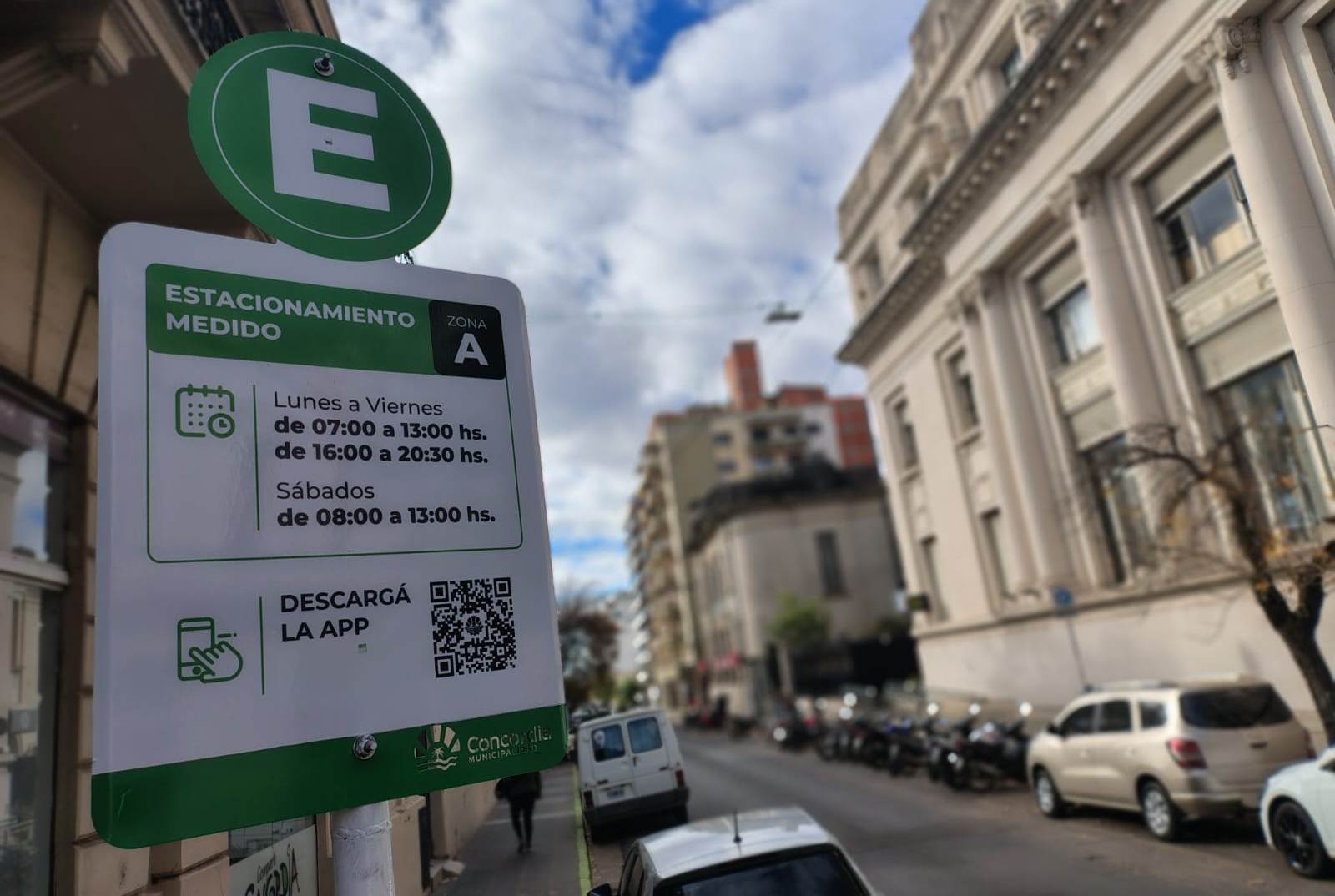 aqlt="Cartel verde del nuevo sistema de estacionamiento medido en Concordia indicando horarios y descarga de app"