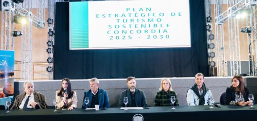 alt="Autoridades de Concordia y Entre Ríos sentadas en una mesa frente a una pantalla que anuncia el Plan Estratégico de Turismo sostenible en Concordia"
