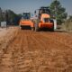 alt="Dos grandes aplanadoras viales de color naranja realizan tareas de compactación de suelo durante el bacheo en la ruta 4 en Entre Ríos"