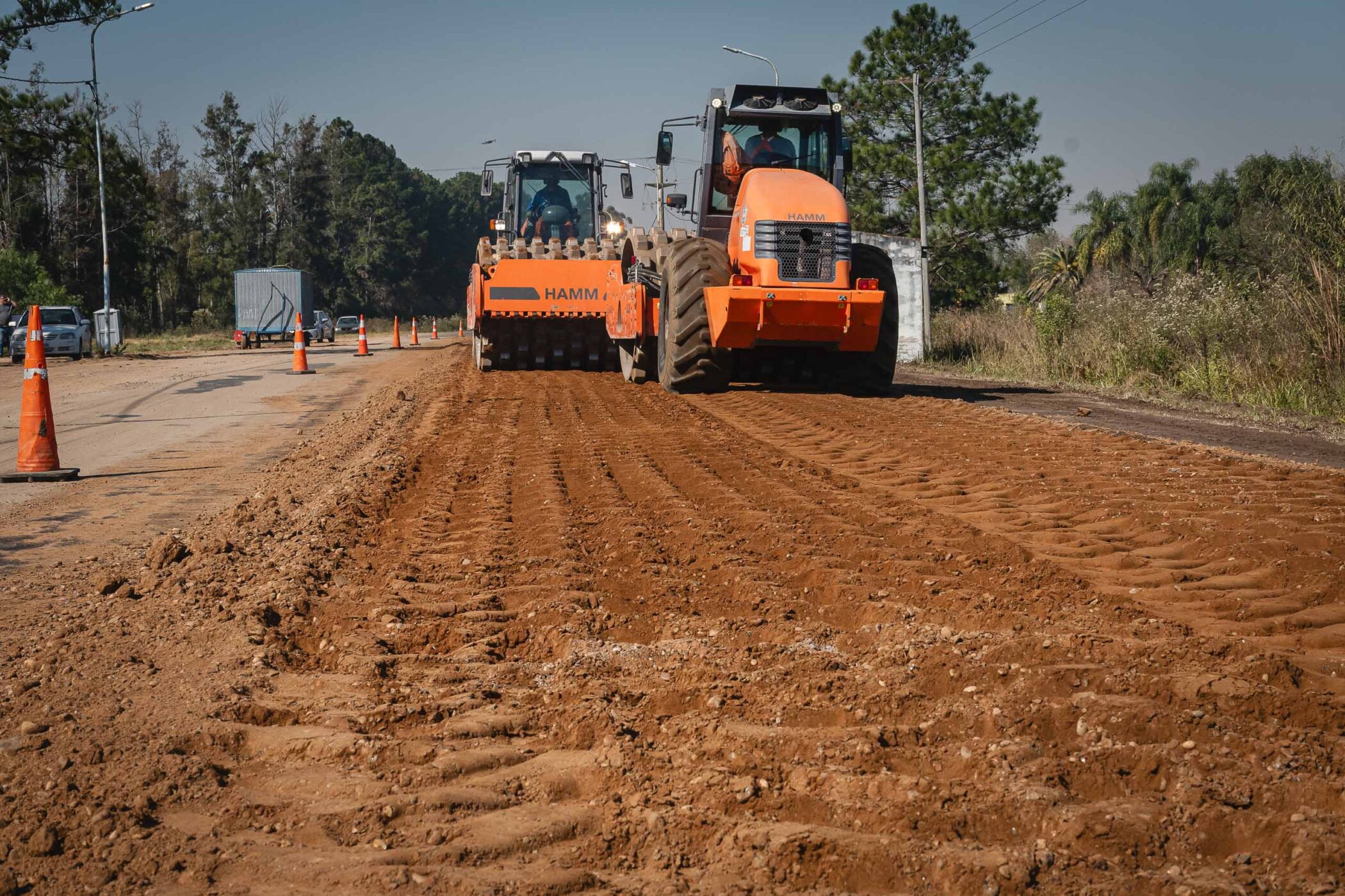 alt="Dos grandes aplanadoras viales de color naranja realizan tareas de compactación de suelo durante el bacheo en la ruta 4 en Entre Ríos"