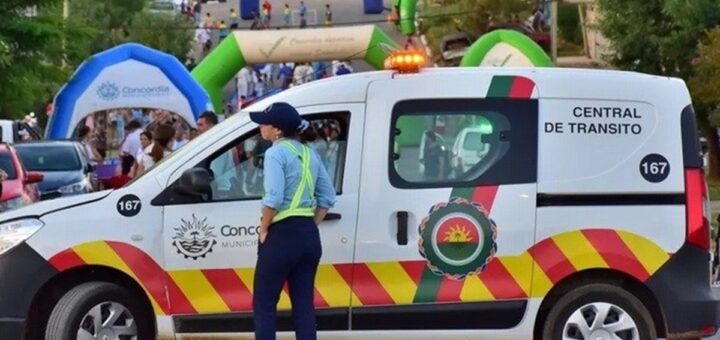 alt="Agente municipal junto a una patrulla vial vigilando los cortes de tránsito en Concordia durante un evento público"