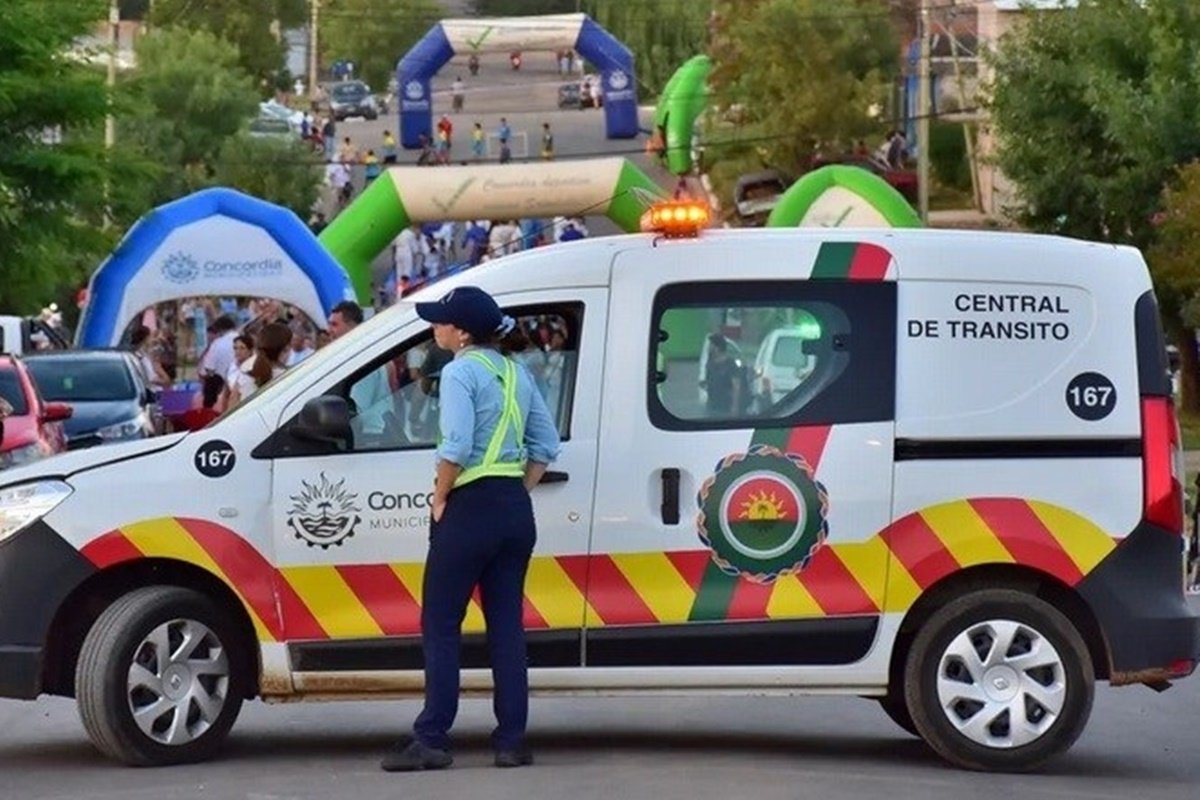 alt="Agente municipal junto a una patrulla vial vigilando los cortes de tránsito en Concordia durante un evento público"