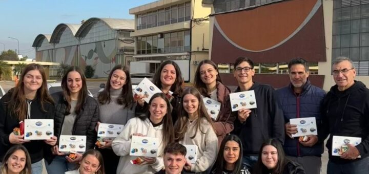 alt=!Docentes y estudiantes de la carrera de Contador Público posan sosteniendo cajas de souvenir frente a la fábrica de Arcor en Córdoba"