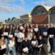 alt=!Docentes y estudiantes de la carrera de Contador Público posan sosteniendo cajas de souvenir frente a la fábrica de Arcor en Córdoba"