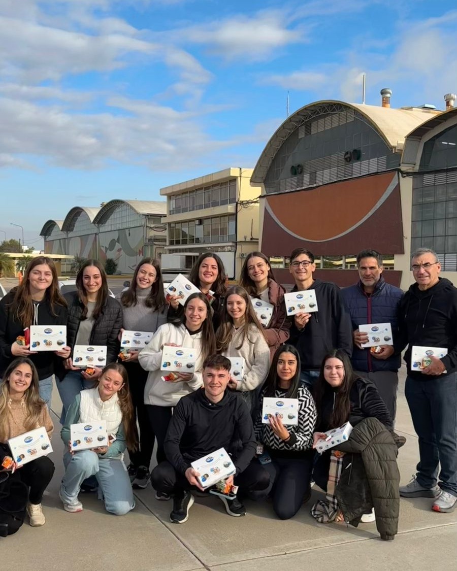 alt=!Docentes y estudiantes de la carrera de Contador Público posan sosteniendo cajas de souvenir frente a la fábrica de Arcor en Córdoba"