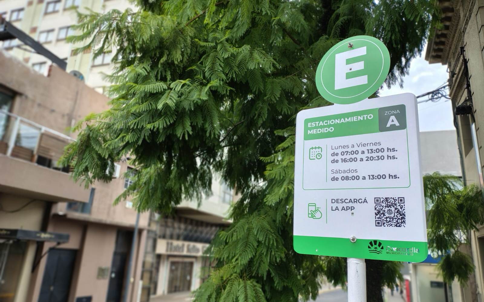 alt="Cartel indicador verde del estacionamiento medido en Concordia con horarios de vigencia e instructivo de descarga de la aplicación móvil"