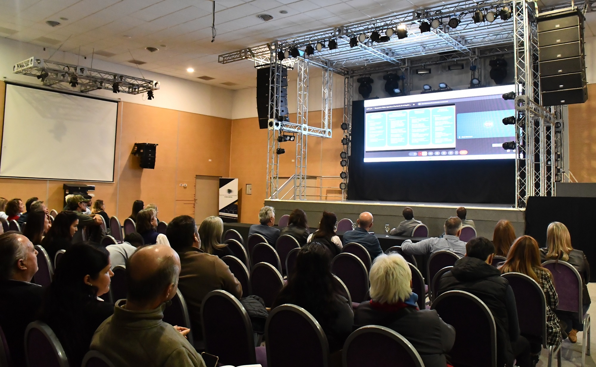 alt="Presentación del polo logístico y puerto fluvial de Concordia en el Centro de Convenciones, con asistentes y proyección en pantalla"
