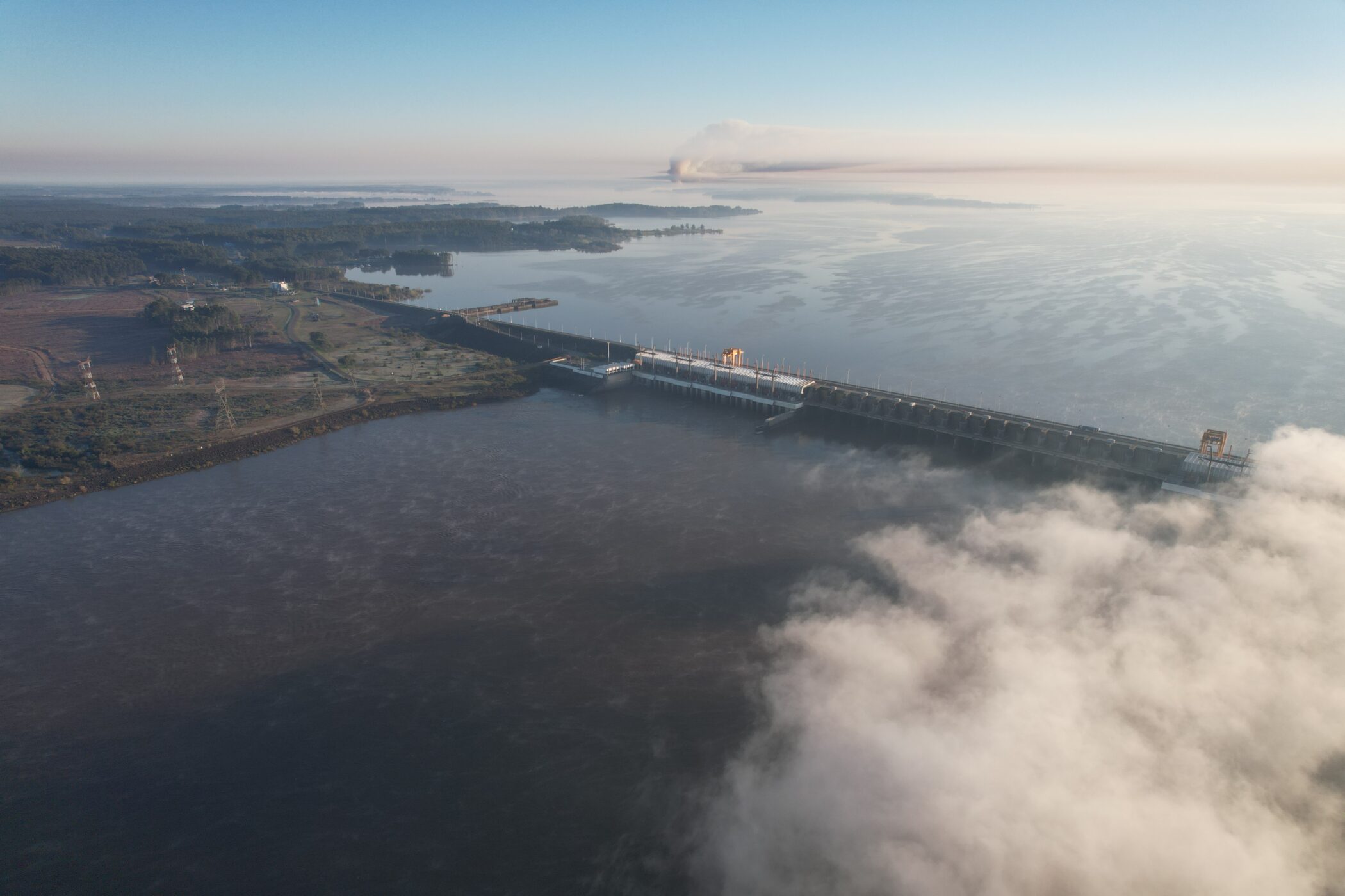 alt="Fotografía aérea de la represa de Salto Grande rodeada de nubes bajas y neblina, ilustrando la preparación frente a El Niño en Salto Grande"